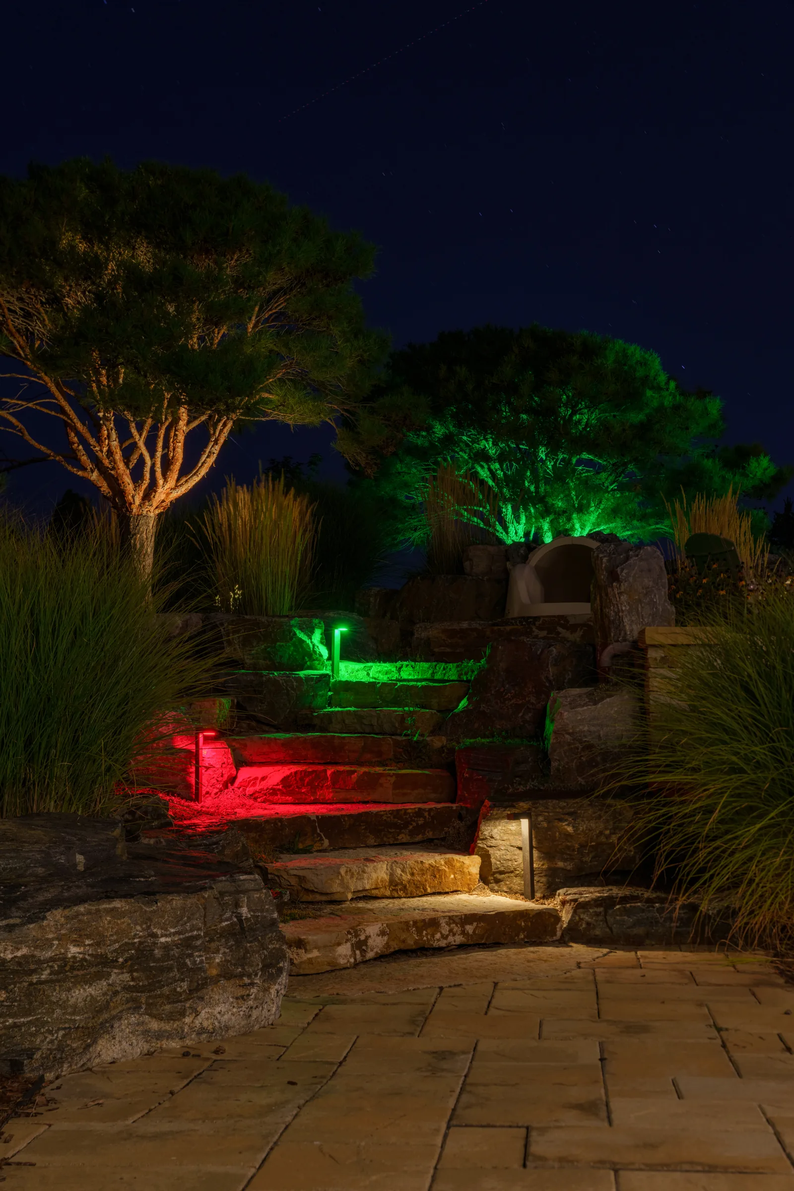 Garden beds and trees lit in green and red with AdaptiV landscape lights