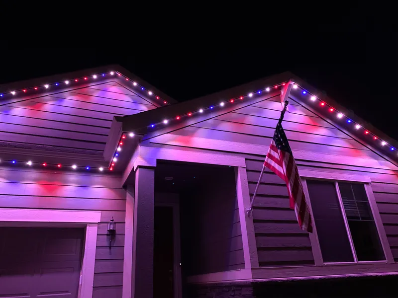 Roofline lit in red, white and blue behind an American flag for the Fourth of July